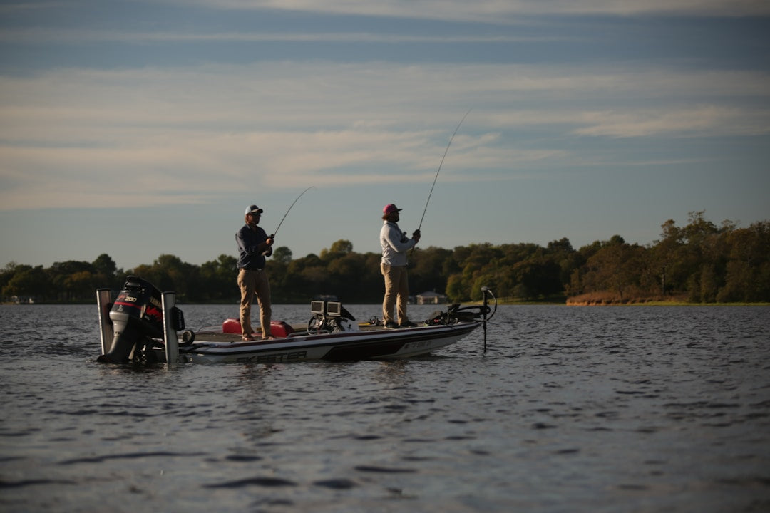 Two anglers bass fishing from a boat on a lake at sunrise