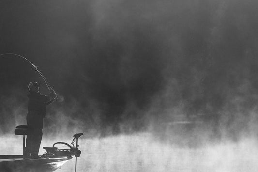a man standing on a boat holding a fishing rod