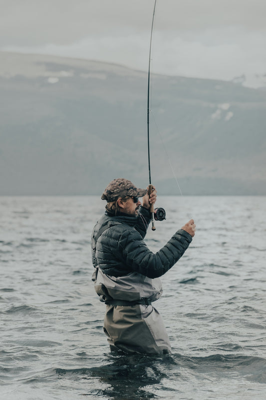 a man standing in the water while holding a fishing rod